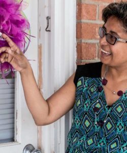 Woman smiles as she points to her wreath on her front door