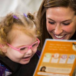 Woman reads to child with pink glasses