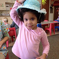 Young girl in pink shirt wears a blue hat