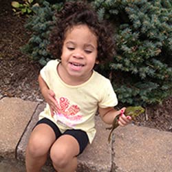 Young girl sits on a wall in a garden