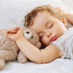 Child sleeps with stuffed bear