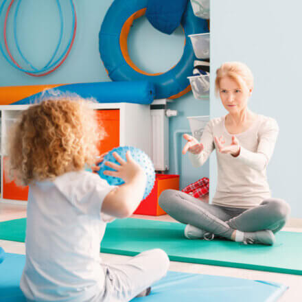 Child Throwing Ball With Therapist